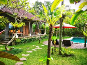 a garden with a house and a swimming pool at Thani Villa Ubud in Ubud