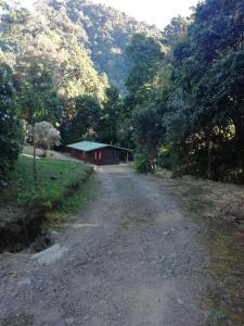 a dirt road with a red building in the distance at Miriam'S Quetzals lodge in San Gerardo de Dota