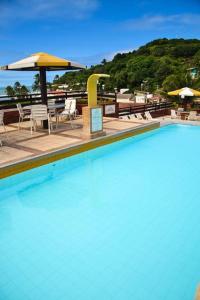 una piscina con sillas, mesas y sombrilla en Flat Pipa's Ocean a passos da Praia e centro Pipa, en Pipa