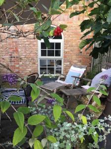a garden with two chairs and a bench in front of a window at The coach house in Grimston