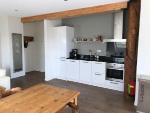 a kitchen with white cabinets and a wooden table at Boerderij de Waard in Anna Paulowna