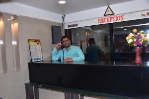 a man talking on a cell phone behind a counter at Rahi Hotel in Mahabaleshwar