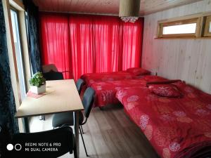 Cette chambre comprend deux lits, une table et des rideaux rouges. dans l'établissement Parila Holiday House with Sauna, à Parila