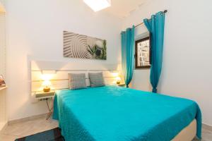 a bedroom with a blue bed and a window at Casa Florinda in Tavira