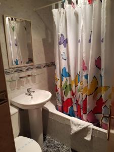 a bathroom with a toilet sink and a shower curtain at Pension los Verdiales in La Herradura