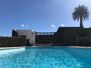 a swimming pool in front of a house with a palm tree at Finca La Fuentecilla in Haría