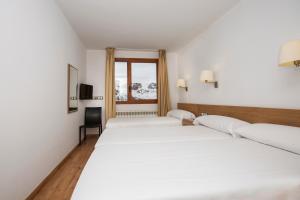 a hotel room with two beds and a window at Hotel Catalunya Ski in Pas de la Casa