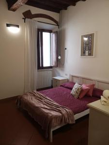una camera da letto con un letto con lenzuola viola e una finestra di Historical J&D a Firenze