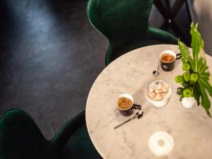 Boutique Hotel K7 في باد ناوهايم: طاولة مع كوبين من القهوة وصحن من الطعام