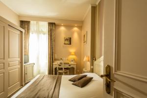 um quarto com uma cama, uma escrivaninha e uma janela em Hôtel du Parc em Montpellier