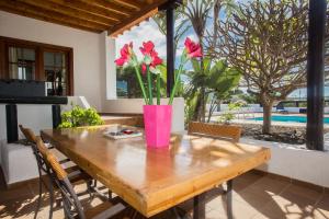 una mesa de madera con flores en un jarrón rosa. en Casa El Quinto, en La Vegueta