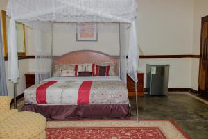 リロングウェにあるMalabi Exclusive Lodgesのベッドルーム(天蓋付きベッド1台、ソファ付)