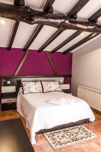ein Schlafzimmer mit einem weißen Bett mit lila Wänden in der Unterkunft Apartamentos Rurales Fuente Chiquita in Hervás