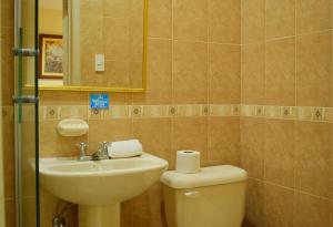 a bathroom with a sink and a toilet and a mirror at Meraki Hotel in Baños