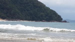 a beach with a bunch of waves in the ocean at Camping Monte Hermom in Ubatuba