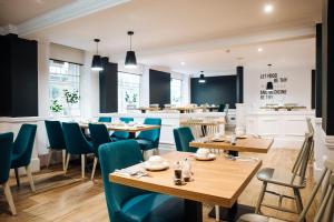 a restaurant with wooden tables and blue chairs at Argyll Apartments in Glasgow