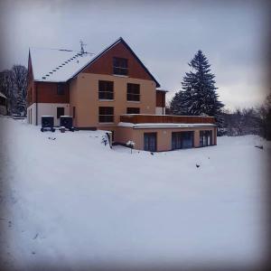 une maison avec de la neige devant elle dans l'établissement Nový Apartmán Říčky, à Říčky