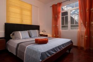 CAPTAIN´S HOUSE في بول دو مار: غرفة نوم مع سرير مع وسادة برتقال عليه
