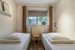 2 camas en una habitación pequeña con ventana en Sfeervol 6 persoons appartement - van alle gemakken voorzien!, en Bakkeveen