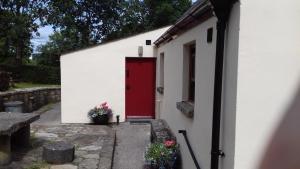 czerwone drzwi na boku białego budynku w obiekcie Millwood Cottage w mieście Lisbellaw