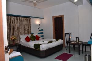 a hotel room with a bed and a table and a desk at Rahi Hotel in Mahabaleshwar