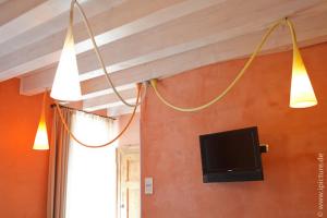 two lights hanging from a wall with a tv at Hotel Remàt in Garda