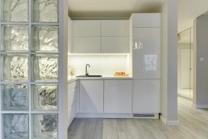 a kitchen with white cabinets and a sink at Apartament Stylowy in Gdynia
