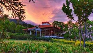 una casa en un campo con una puesta de sol en el fondo en Hotel Altocerro en Constanza