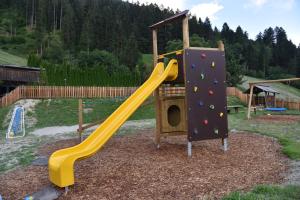 een speeltuin met een gele glijbaan en een speelstructuur bij Pension Gasthof Haselstaude in San Leonardo in Passiria