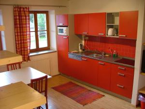 a kitchen with red cabinets and a table and a window at Apartmány Nové Hutě in Nové Hutě