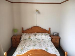 a bed with a wooden headboard in a bedroom at Muckross School House in Kilcar