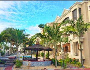 a resort with palm trees in front of a building at Abrico Apartment in Trou aux Biches