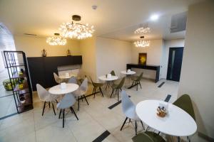 a restaurant with white tables and chairs and chandeliers at Golden Hotel in Bishkek