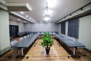 uma sala de conferências com mesas longas e um vaso de plantas em Golden Hotel em Bishkek