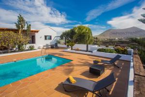 une villa avec une piscine et des montagnes en arrière-plan dans l'établissement Casa El Quinto, à La Vegueta