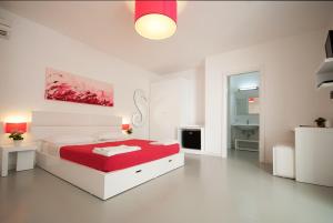 una camera bianca con letto rosso e bagno di Hotel Beach Salento a Marina di Pescoluse