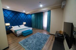 a bedroom with a bed and a blue wall at Golden Hotel in Bishkek