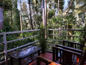 a balcony with two benches and trees in the background at StaySimple Spicefarm in Somvārpet
