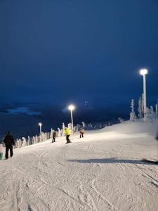 a group of people skiing down a snow covered slope at night at Gościniec ELLA INN Lipniki in Lipniki