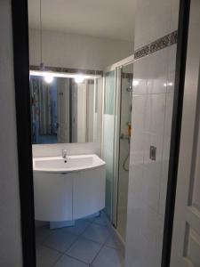 La salle de bains blanche est pourvue d'un lavabo et d'une douche. dans l'établissement Villa avec piscine, au Cap d'Agde