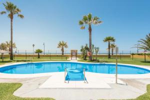 une chaise bleue est installée en face d'une piscine bordée de palmiers. dans l'établissement Livingtarifa Apartamento Serendipia, à Tarifa