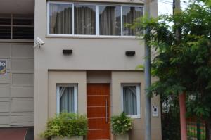 a white building with a brown door and windows at Hotel Jardin De Iguazu in Puerto Iguazú