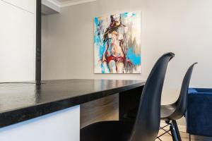 a desk with two chairs and a painting on the wall at Fabulous apartment in heart of Katowice in Katowice