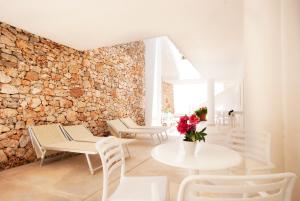 a room with tables and chairs and a stone wall at Hotel Beach Salento in Marina di Pescoluse