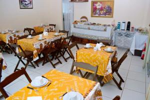 a dining room with tables and chairs with yellow table cloth at Hotel e Pousada Boulevard de Itapoa in Itapoa