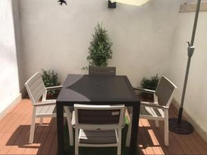 une table noire avec des chaises blanches et une plante en pot dans l'établissement Amazing flat in Madragoa, à Lisbonne