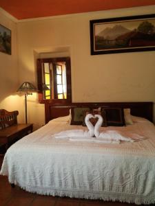 Un dormitorio con una cama con dos cisnes. en Posada San Sebastian, en Antigua Guatemala