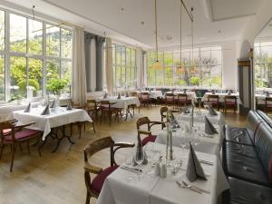 um restaurante com mesas e cadeiras brancas e janelas em Hotel Kaiserin Augusta em Weimar