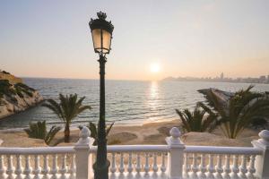 a street light in front of a beach with the sunset at Sant Vicent 35 in heart of Old town in Benidorm