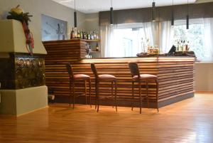 a bar with four stools in front of a counter at Family Hotel Gran Baita in Pozza di Fassa